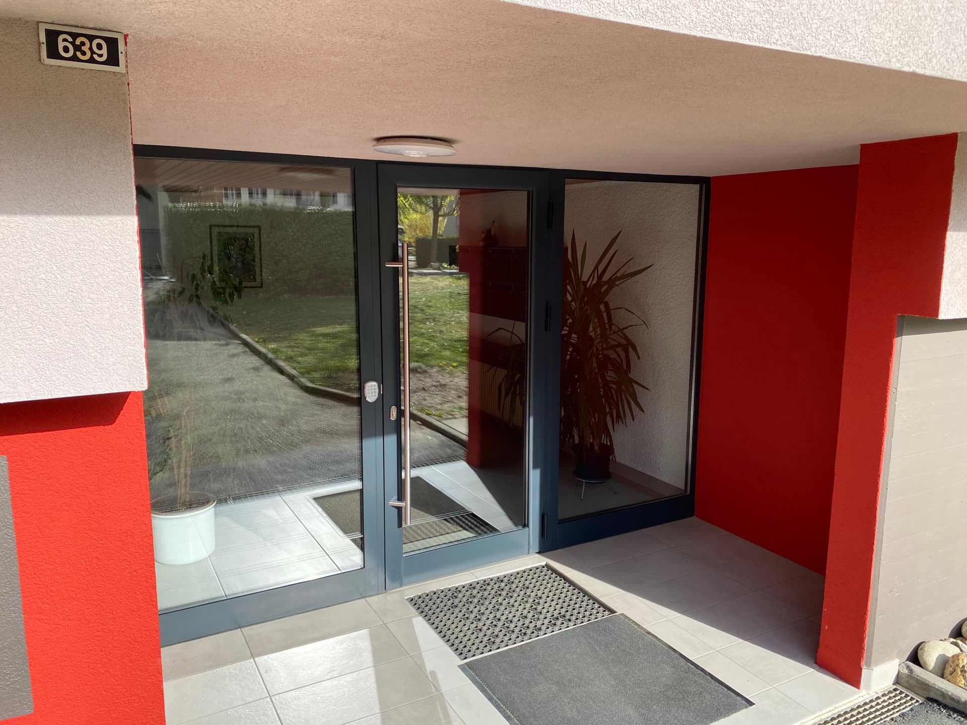 Entrée d’immeuble : porte et châssis vitrés en aluminium anthracite — Etangs 1 & 2, Penthalaz (VD)